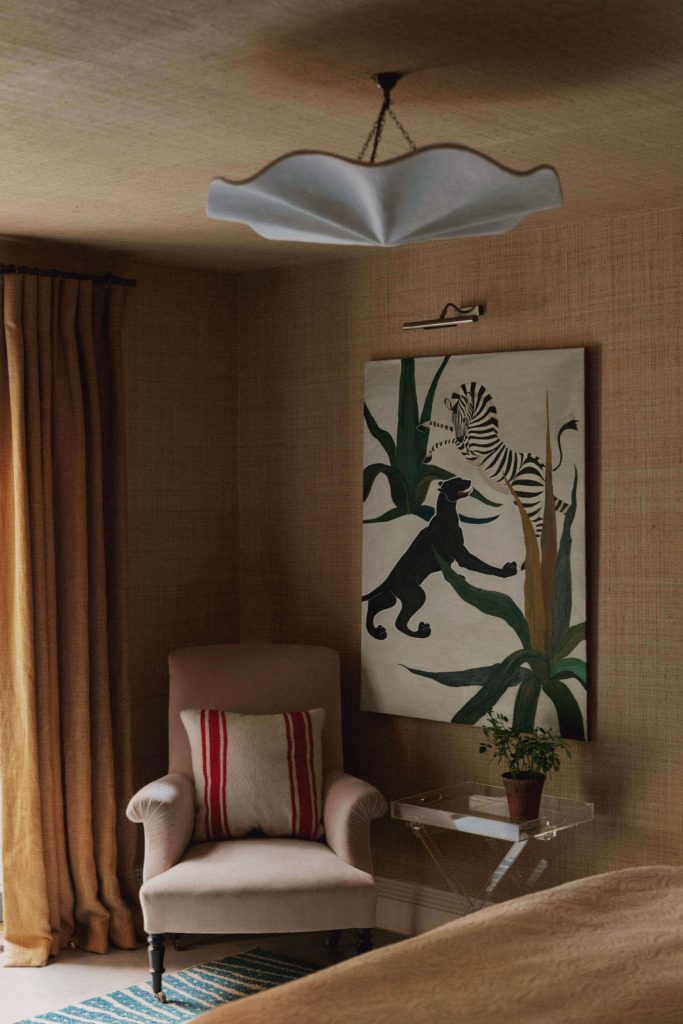 a seating area in a bedroom with neutral toned, grass cloth texture wallpaper that covers all wall and the ceiling 