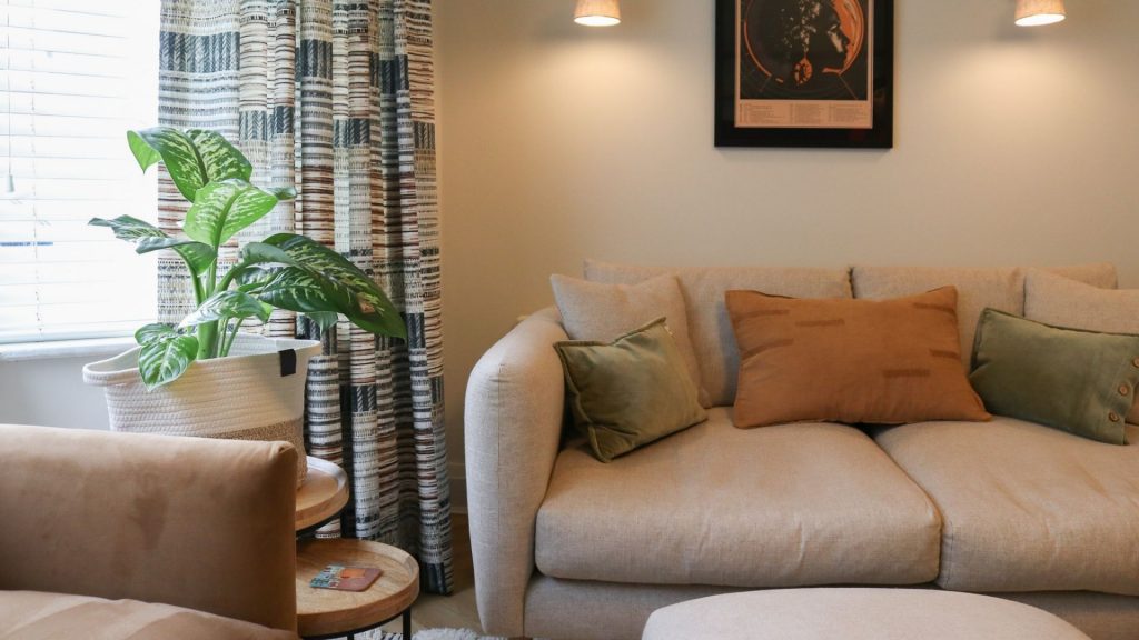 An image of a living room interior with a neutral colour palette. The image focuses on a closeup of a two person sofa.