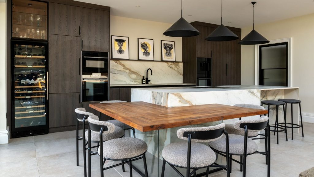 A kitchen island designed with a lowered breakfast bar and seating area attached.